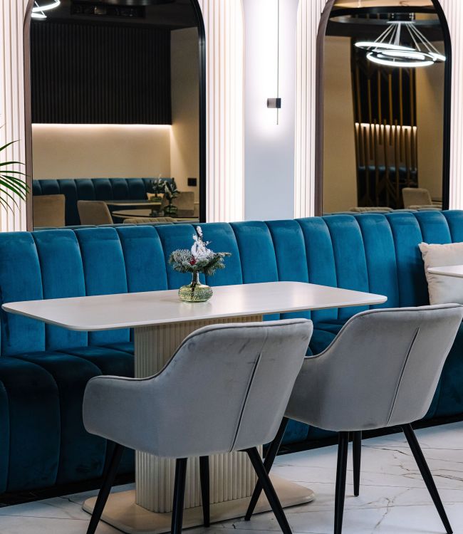 Elegant cafe interior showcasing a chic blue velvet sofa, marble flooring, and sophisticated lighting